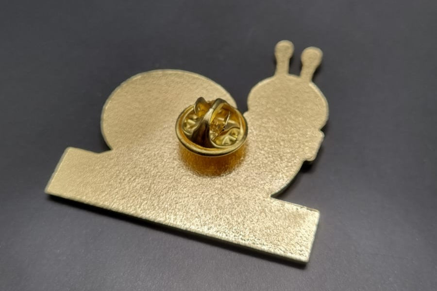 Gold snail-shaped pin on a dark gray background